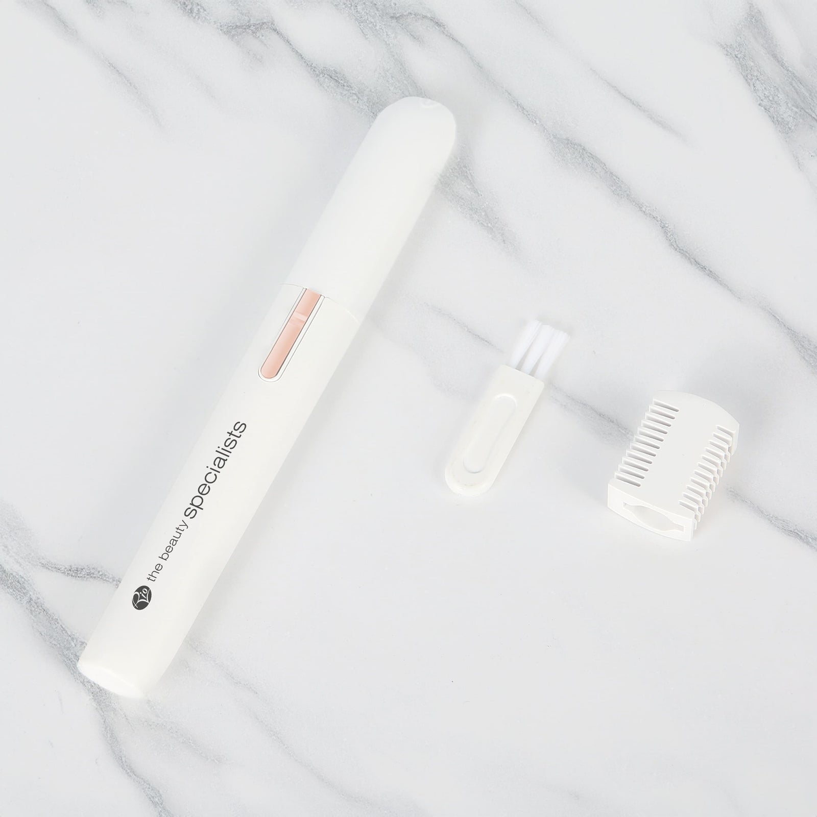 The Rio Precision Eyebrow, Face & Body Hair Trimmer in white with a pink button comes with a cleaning brush and white attachment, shown on a white marble surface.