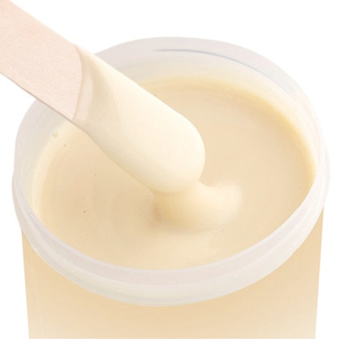 spatula dipped in pot of deluxe soft creme wax