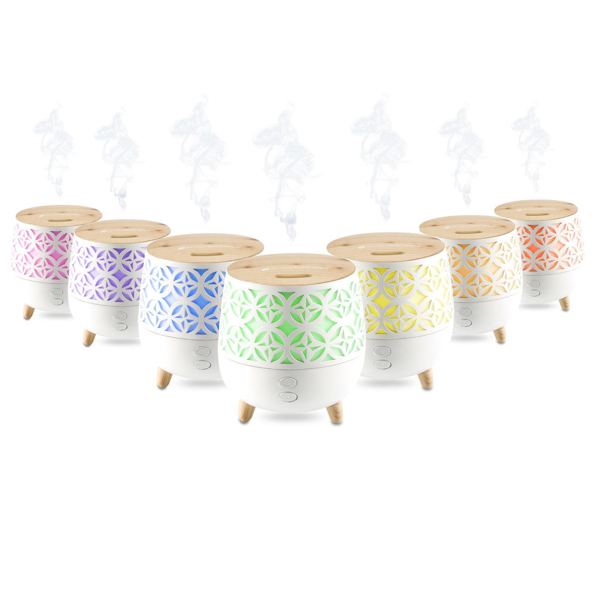 A row of seven Rio TALIA Aroma Diffuser, Humidifier & Night-Lights with wooden tops and white bases emit mist and glow in pink, purple, blue, green, yellow, orange, and red through geometric cutouts.