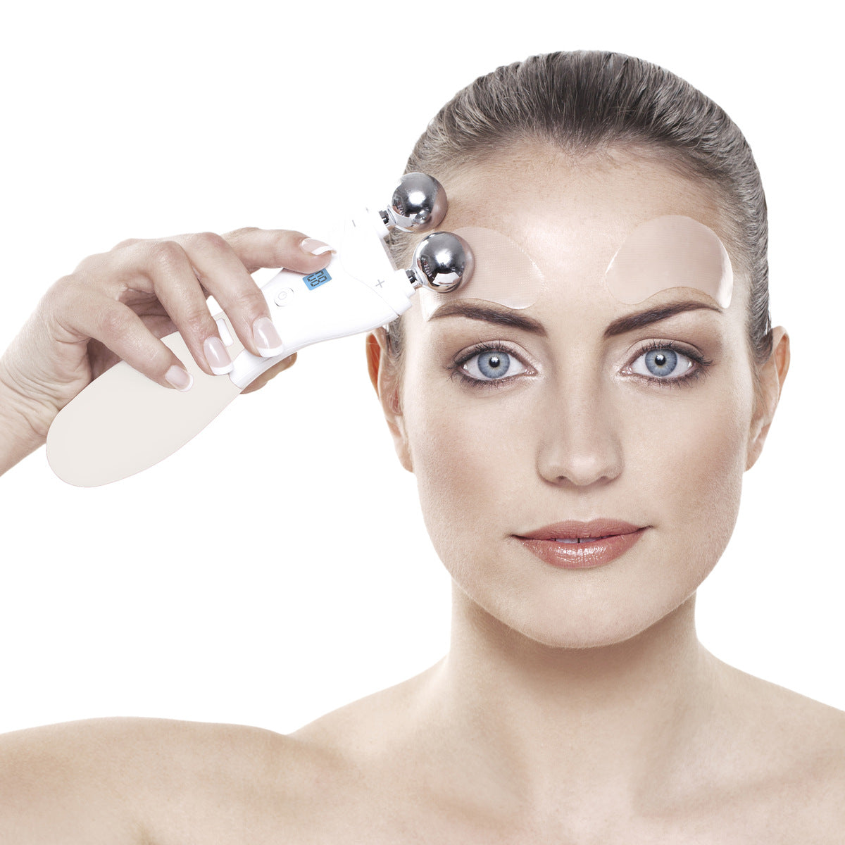 A woman with blue eyes holds the Rio Lift Plus 60 Second Face Lift, using transparent gel patches on her forehead and under her eyes for rejuvenation. Her expression remains neutral as she applies the device’s two metal spheres to her forehead.