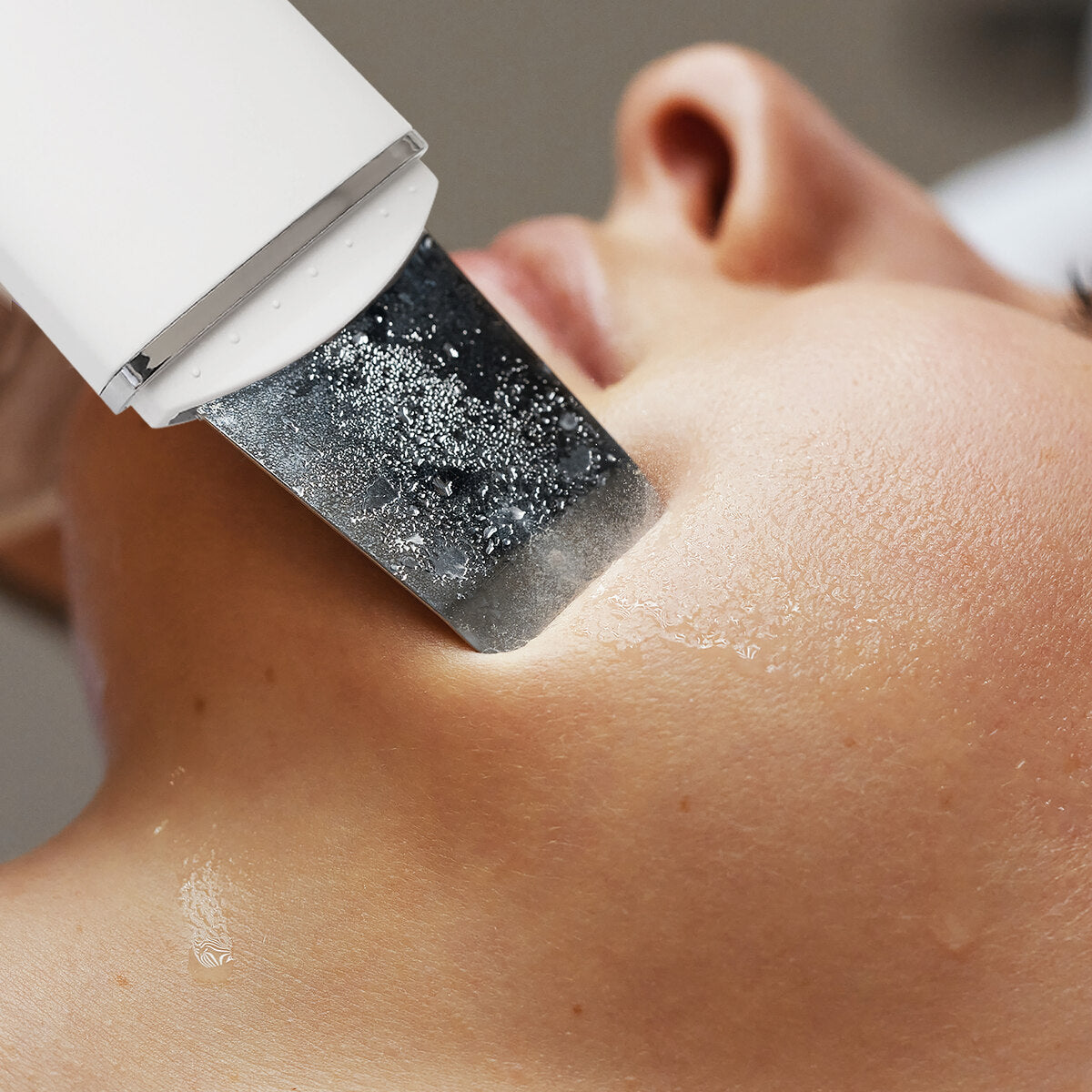 A close-up of a person’s lower face as the Rio Ultrasonic Skin Cleanser is used on their wet chin for deep exfoliation and skin cleansing.