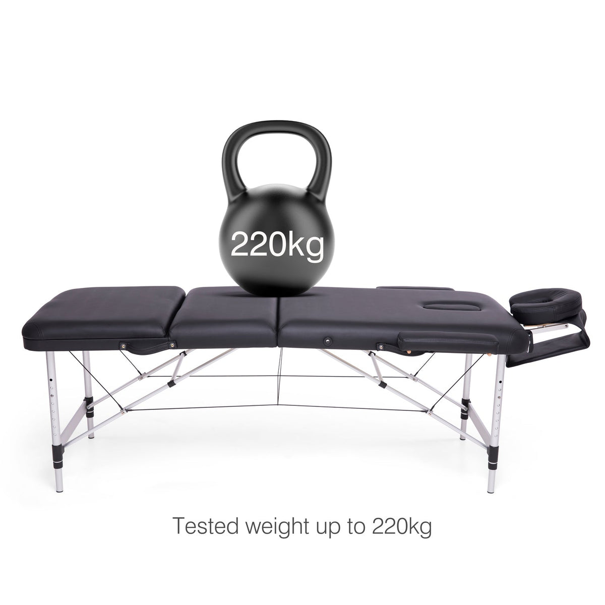 The Rio Professional Aluminium Massage Table & Treatment Couch in black supports a 220kg black kettlebell. Text below states: Tested to 220kg—perfect for home massage or as a durable treatment couch.