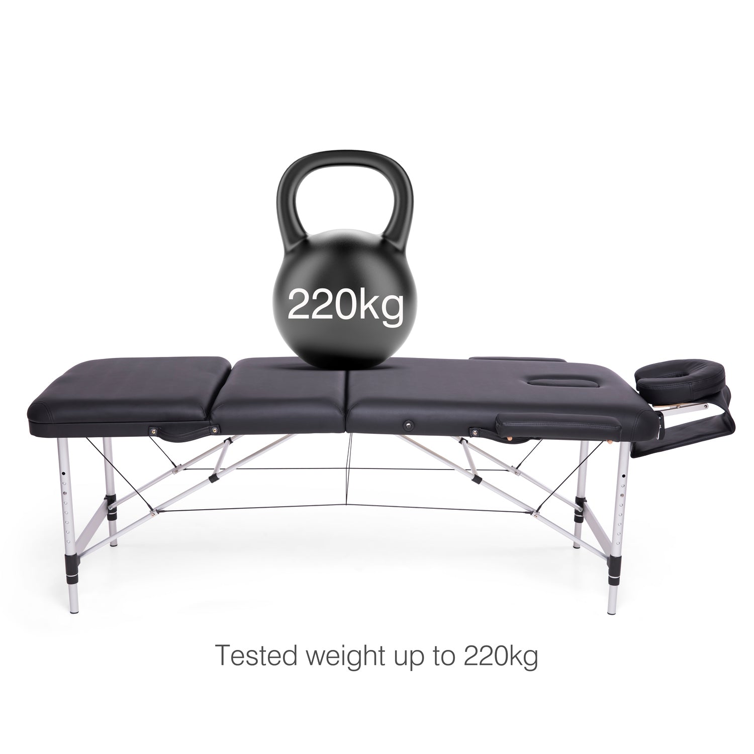 The Rio Professional Aluminium Massage Table & Treatment Couch in black supports a 220kg black kettlebell. Text below states: Tested to 220kg—perfect for home massage or as a durable treatment couch.