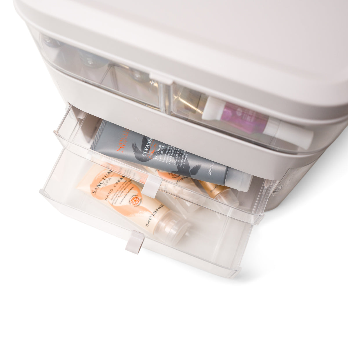 A close-up of the Rio Ultimate Beauty Storage Box With Dimmable Mirror in light gray, featuring transparent drawers filled with skincare and cosmetic products. One drawer is partially open, revealing the neatly arranged items inside.