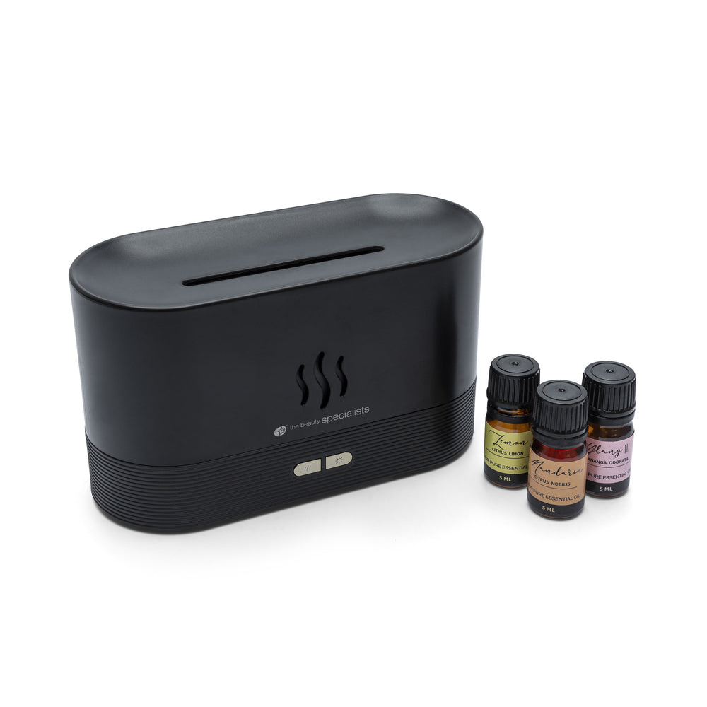 The Rio ALTA Aroma Diffuser, Humidifier and Night-light in black sits beside three colorful essential oil bottles, all displayed against a white background.