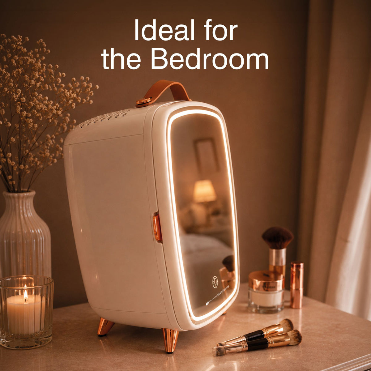 A Rio Beauty Skincare Fridge With Mirror featuring a mirrored door and LED lights sits on a bedroom vanity beside cosmetics, makeup brushes, a candle, and a vase; text reads: Ideal for the Bedroom and perfect for chilled storage of your favorite creams.