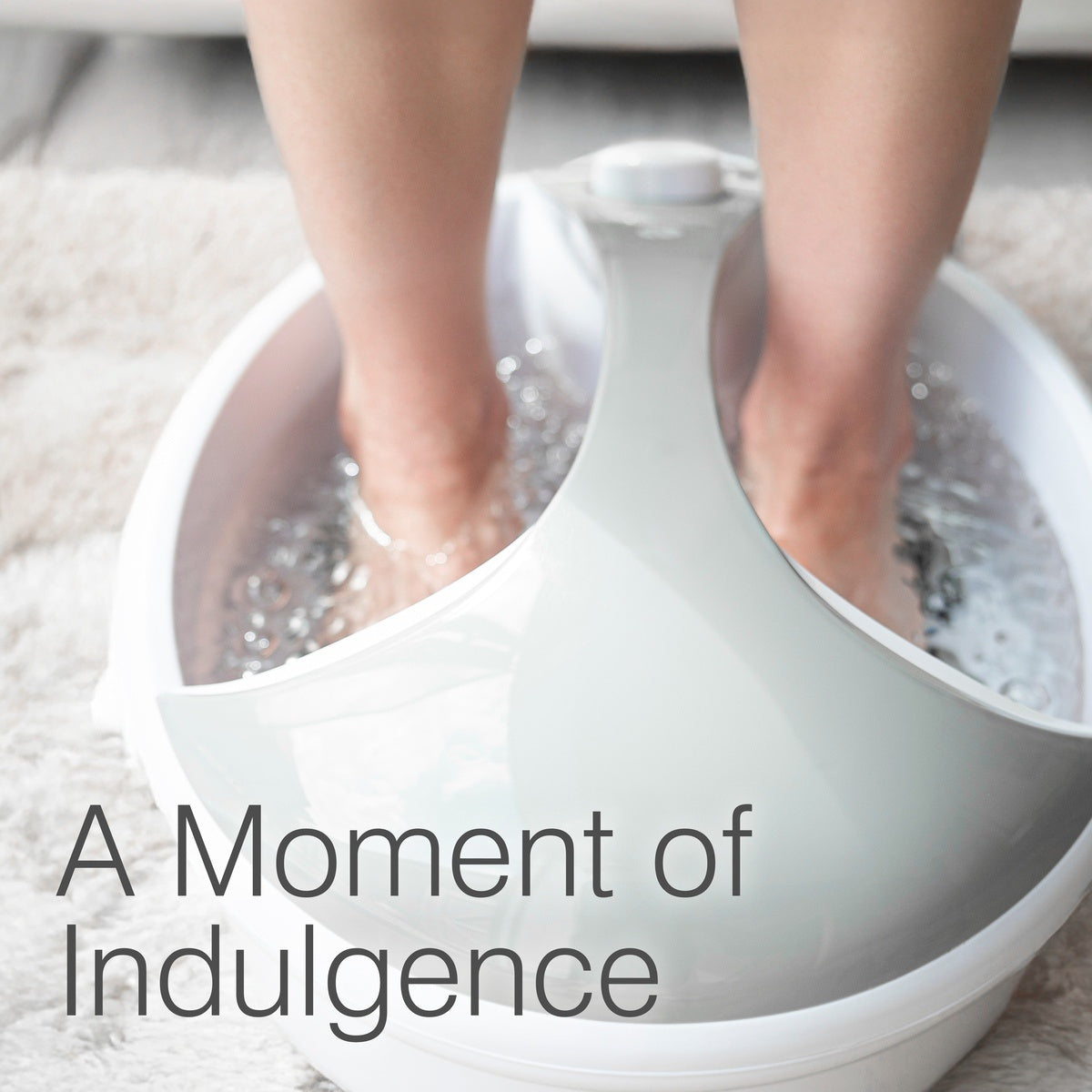 A person relaxes with their feet in the Rio Deluxe Foot Spa Bath and Massager, filled with water, under the words "A Moment of Indulgence.