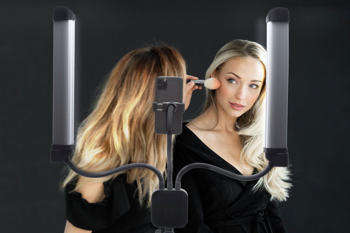 A woman uses the Rio Professional Twin LED Strip Lights with a mounted smartphone, creating the perfect setup for makeup artists or content creators, all set against a dark backdrop.