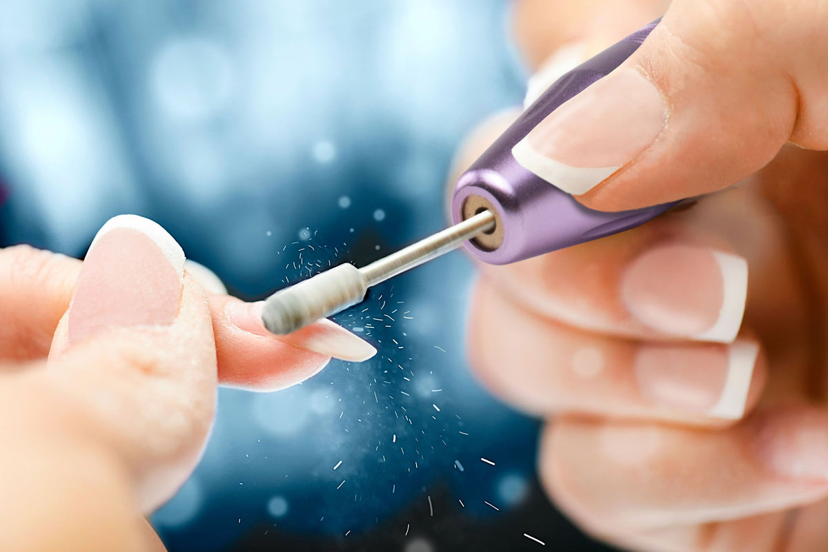 close up of drill head rotating on the nail to file down acrylic nail