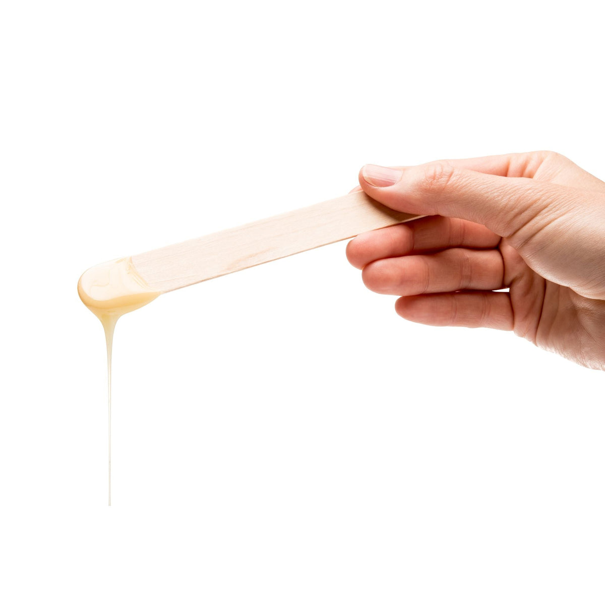 hand holding wooden spatula with melted wax dripping off 