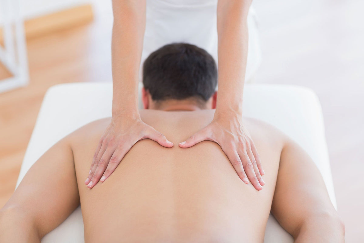 A person enjoys a back massage while lying face down on the Rio Professional Ultra-Light Portable Massage Table, as a therapist works on their upper back in a calm, well-lit setting.