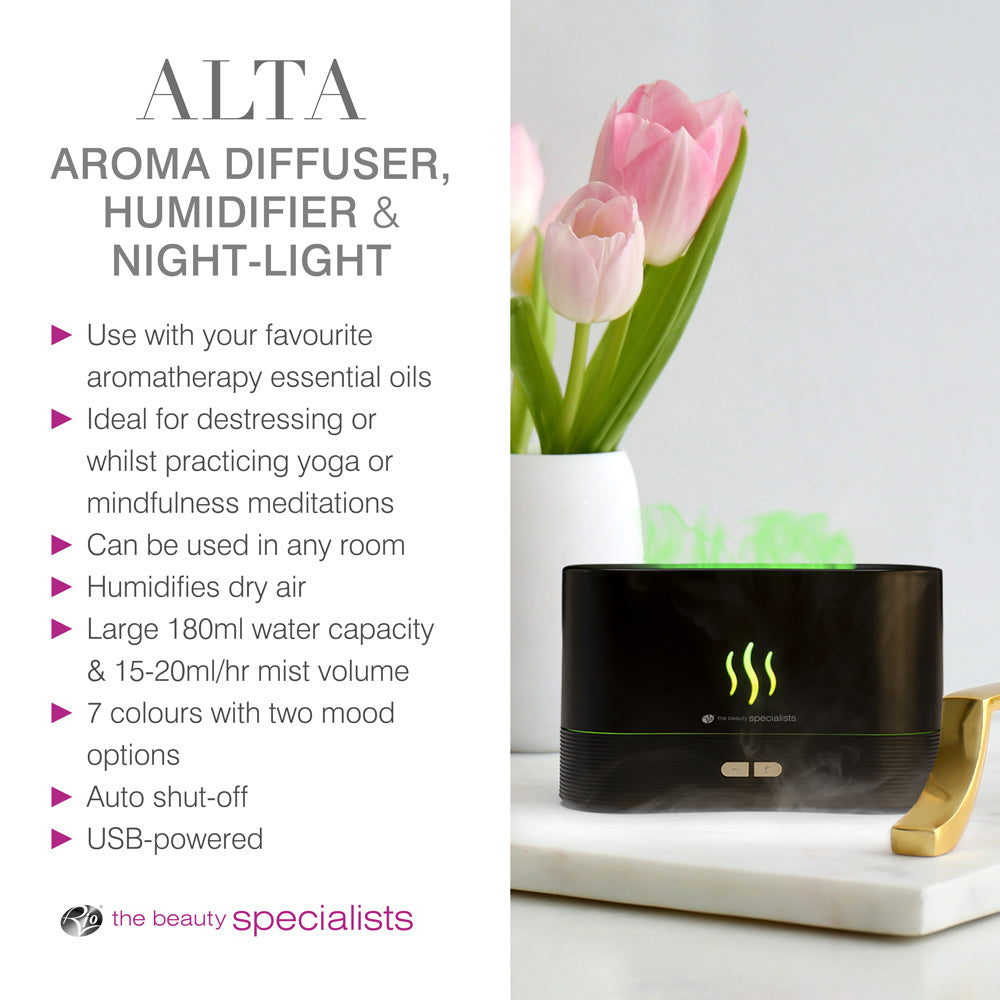 The ALTA Aroma Diffuser, Humidifier and Night-light by Rio sits on a white table with flowers and a towel. It features essential oil use, auto shut-off, USB power, 7 LED colors, night-light mode, and a 180ml capacity.