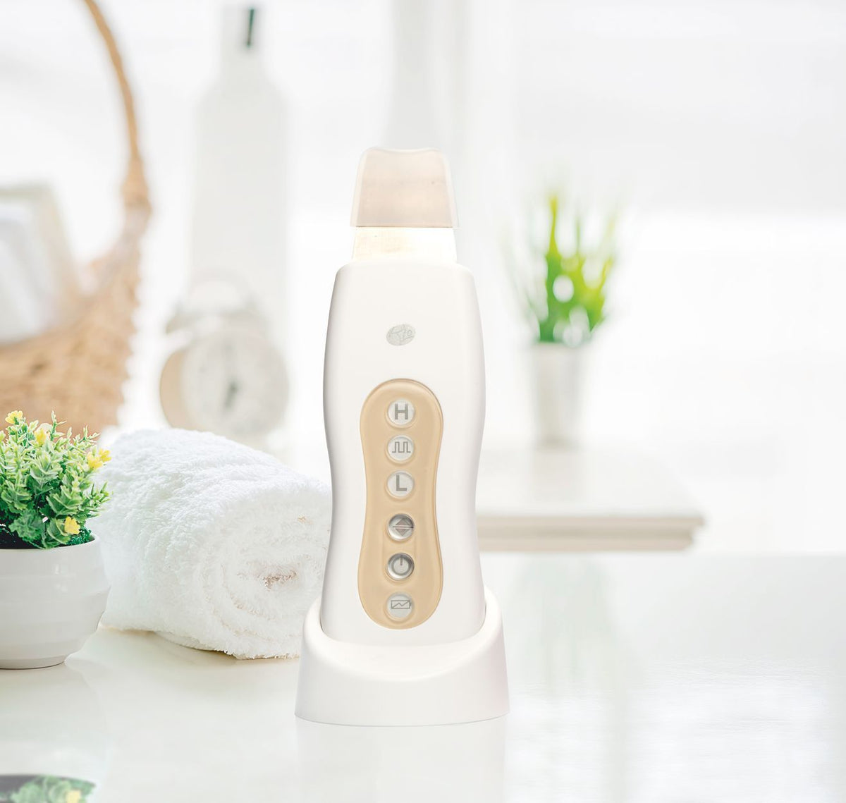 ultrasonic facial device in stand in spa like setting with folded fluffy towel and potted plant 