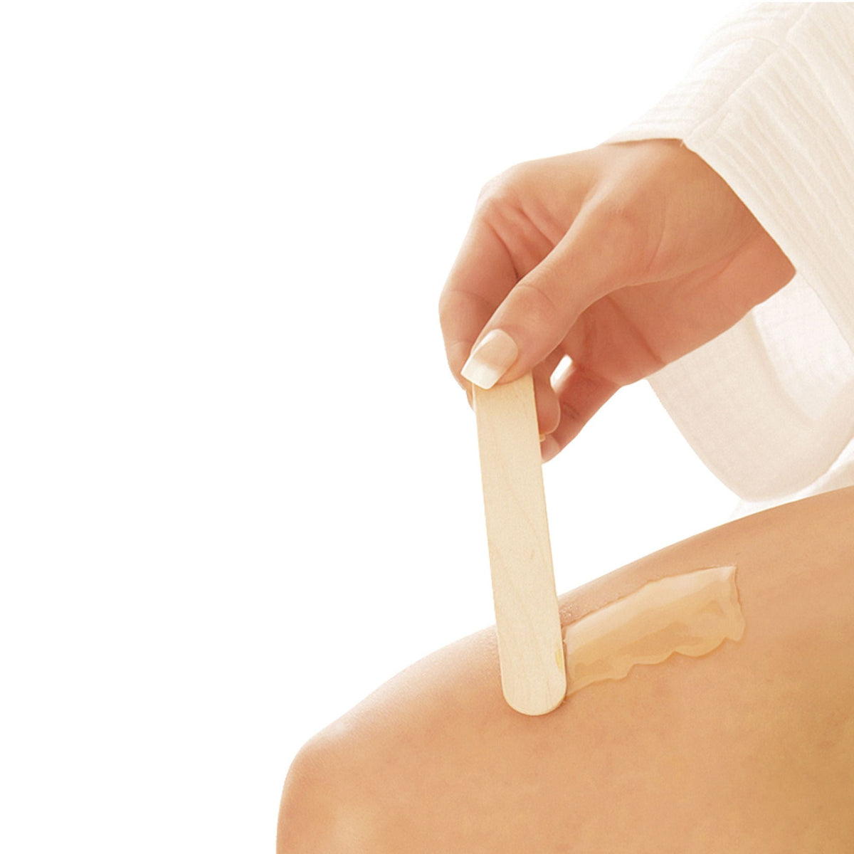 lady applying wax to leg with wooden spatula