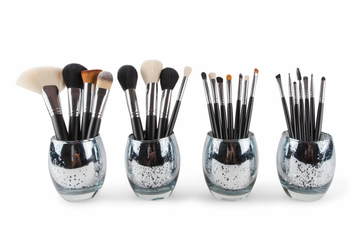 The Rio PROFESSIONAL SALON MAKEUP BRUSH COLLECTION & BELT includes four black-handled brushes—fan, angled, fluffy, and precision—displayed in glass holders against a white background, perfect for salon brush organization.